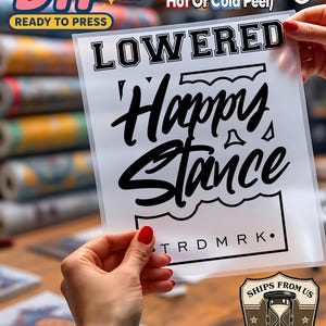 May include: A clear DTF (Direct to Film) transfer sheet with the words "LOWERED Happy Stance" in black. The sheet also includes the text "TRDMRK." and instructions for application. The DTF transfer is ready to press.
