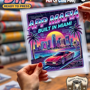 May include: A DTF (Direct to Film) transfer sheet with the text "APP MAFIA BUILT IN MIAMI" featuring a red sports car, palm trees, and a city skyline. The sheet is held up by a person with red nail polish. The sheet is ready to press.