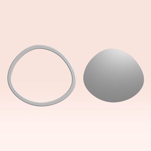 以下が含まれることがあります： 淡いピンク色の背景に、2つの灰色の抽象的な形をしたオブジェクトがあります。1つは丸みを帯びた不規則なリングで、もう1つは滑らかな楕円形です。オブジェクトは3Dレンダリングされているようです。