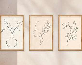 May include: Three rectangular wall art prints in light wood frames. The left print shows a line drawing of a vase with branches. The centre print features a profile of a face with leaves. The right print displays a single leafy branch line drawing.