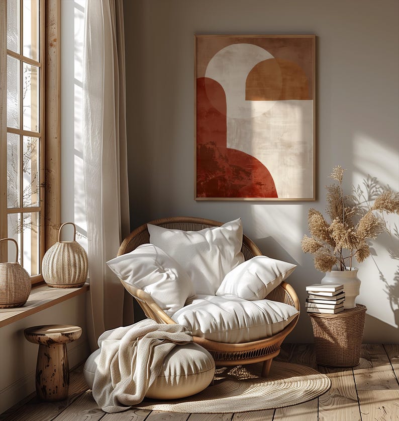 May include: A comfortable living room scene with a rattan chair and white cushions, a framed abstract artwork in warm colours, and a small side table. Natural light streams through a window, creating a relaxing atmosphere.