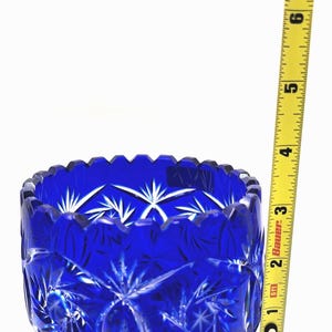 Op de afbeelding: Een levendige kobaltblauwe glazen kom met een sterrenpatroon. De kom heeft een geschulpte rand en meet ongeveer 7.6 cm in diameter. De kom is gemaakt van geslepen glas en staat op een witte achtergrond.