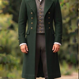 May include: A dark green long coat with double-breasted gold buttons, worn over a grey vest with matching buttons and a white collared shirt with ruffled cuffs. The outfit includes dark grey trousers and black knee-high leather boots.