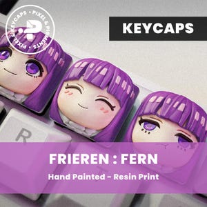Op de afbeelding: Drie aangepaste keycaps met een cartoonpersonage met paars haar en ogen. De keycaps zijn handgeschilderde harsafdrukken. Het woord "KEYCAPS" staat in een zwarte rechthoek boven de keycaps. De tekst "FRIEREN : FERN" staat in een paarse rechthoek eronder.