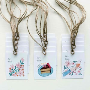 May include: Set of ten white gift tags with twine attached. The tags feature three different designs: a floral pattern, a birthday cake with candles, and a champagne glass with the text "let's celebrate".
