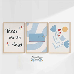 Op de afbeelding: Drie ingelijste kunstdrukken. De linkerafdruk leest "These are the days" met steraccenten. De middelste print toont een blauwe staatsvorm met het woord "Lawrence". De rechterprint heeft blauwe bloemen en een gele zon.