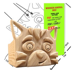 May include: A wooden cat-shaped box, crafted from light-colored wood. The box features detailed scroll saw work, including the cat's face, ears, and a smiling mouth. The image also shows a pattern for scroll saw projects, with text that reads "Wooden Animal Box" and "PDF for Scroll Saw".