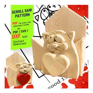May include: A wooden scroll saw pattern for a cat-shaped holder with a red heart. The holder is made of light-colored wood. The image includes text that says "SCROLL SAW PATTERN" and "PDF/SVG/DXF FILES Instant Download."