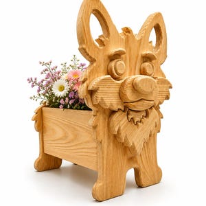 May include: A wooden planter shaped like a cartoon dog, filled with colorful flowers. The planter is made of light-colored wood and features carved details, including the dog's face, ears, and paws. The flowers include pink, white, and purple blooms.