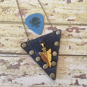 May include: A blue leather necklace with a gold arrow pendant and a blue guitar pick that says "D'Addario USA 1.0 mm".