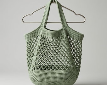 May include: A sage green, crocheted tote bag with a diamond-patterned mesh design. The bag has two handles and a rounded bottom. It is hanging on a silver metal hanger. The bag is made of a soft, textured yarn.