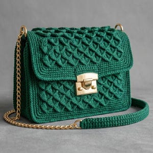 May include: A handcrafted, emerald green crochet handbag with a textured, geometric pattern. The bag features a gold-colored clasp and chain strap. The bag is a stylish accessory.