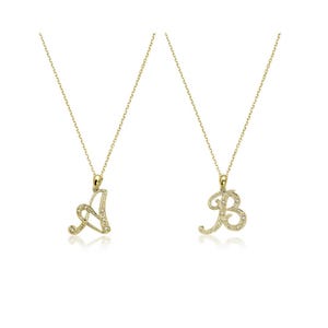 Puede incluir: Dos collares con iniciales doradas, uno con la letra "A" y otro con la letra "B". Cada colgante está incrustado con pequeñas piedras preciosas transparentes y cuelga de una delicada cadena. Los colgantes están en fuente cursiva.