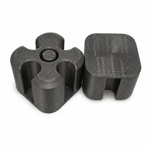 May include: Two dark gray 3D-printed objects. One is a four-lobed shape with a central circular feature. The other is a square shape with a curved cutout on one side. Both objects have visible layer lines from the printing process.