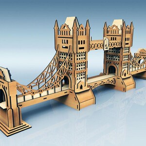 May include: A wooden model of the Tower Bridge, featuring intricate cut-out details. The model is made of light brown wood and has a detailed design of the iconic London landmark. The bridge spans across a light blue surface.