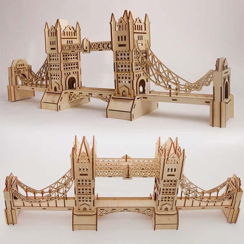 May include: Two wooden model replicas of the Tower Bridge in London. The models are made of light-colored wood and feature intricate cut-out details. The bridges have towers and suspension sections, showcasing architectural design.