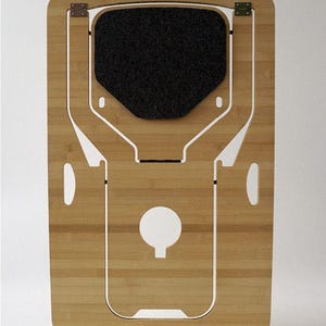 Op de afbeelding: Een bamboe laptopstandaard met een zwart vilten kussen en witte accenten. De standaard heeft een uitgesneden handvat en ventilatiegaten. De merknaam "MONSTRANS" staat onderaan.