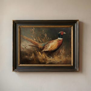 May include: An oil painting of a pheasant standing in tall, dry grass. The bird features a red face, a dark blue neck, and brown, tan, and black patterned feathers. The artwork is enclosed in a dark, distressed wooden frame with gold trim.