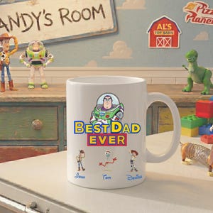 Puede incluir: Una taza de cer&aacute;mica blanca con un gr&aacute;fico de Buzz Lightyear sobre el texto "BEST DAD EVER". Debajo del texto hay ilustraciones de Woody, Forky y Jessie con los nombres "John", "Tom" y "Denise" impresos en letra azul debajo.