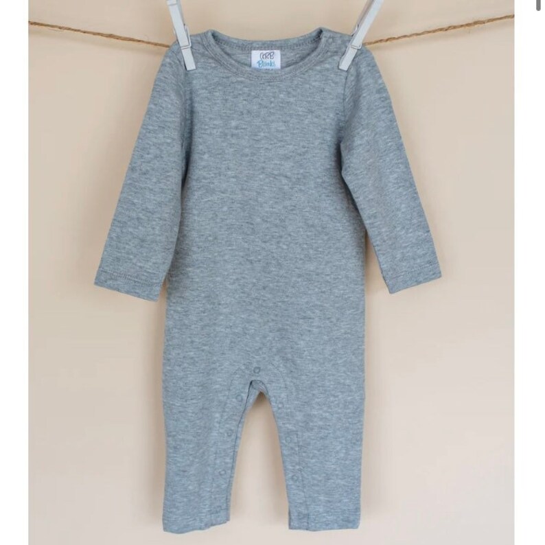 May include: Gray long-sleeve baby onesie with snap closures. The onesie has a small white tag with the text "000 Blank" on it.