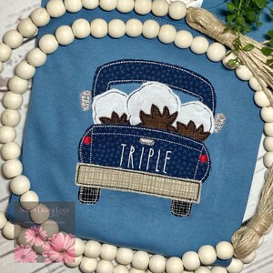 May include: A blue pickup truck with a white star pattern is filled with three white cotton bolls. The truck has the word "TRIPLE" written on the back.