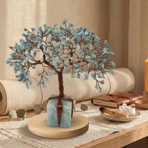 Könnte beinhalten: Eine dekorative Baumskulptur mit braunem Stamm und Ästen, verziert mit hellblauen Edelsteinblättern. Der Baum steht auf einem Holzsockel, mit einem hellblauen quadratischen Sockel. Eine zusammengerollte Yogamatte und eine Kerze sind im Hintergrund.