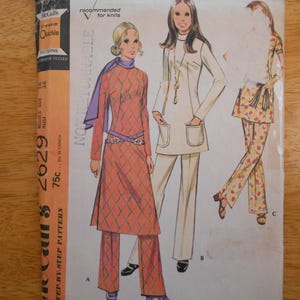 May include: A McCall's 2629 sewing pattern envelope featuring illustrations of three outfits: a long-sleeved tunic with a diamond pattern and pants, a solid-colored long-sleeved tunic with pockets and pants, and a floral print tunic with matching pants.