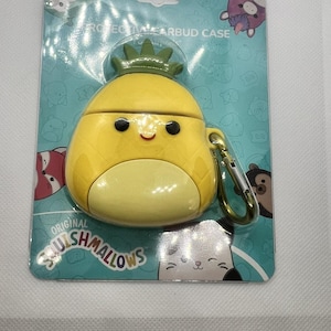 May include: A yellow pineapple-shaped earbud case with a green crown, attached to a teal backing. The case has a gold-colored clasp. The packaging reads "PROTECTIVE EARBUD CASE" and "ORIGINAL SQUISHMALLOWS".