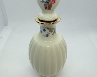 Frasco de perfume Lenox color marfil y dorado con estampado floral y tapón en forma de corazón.