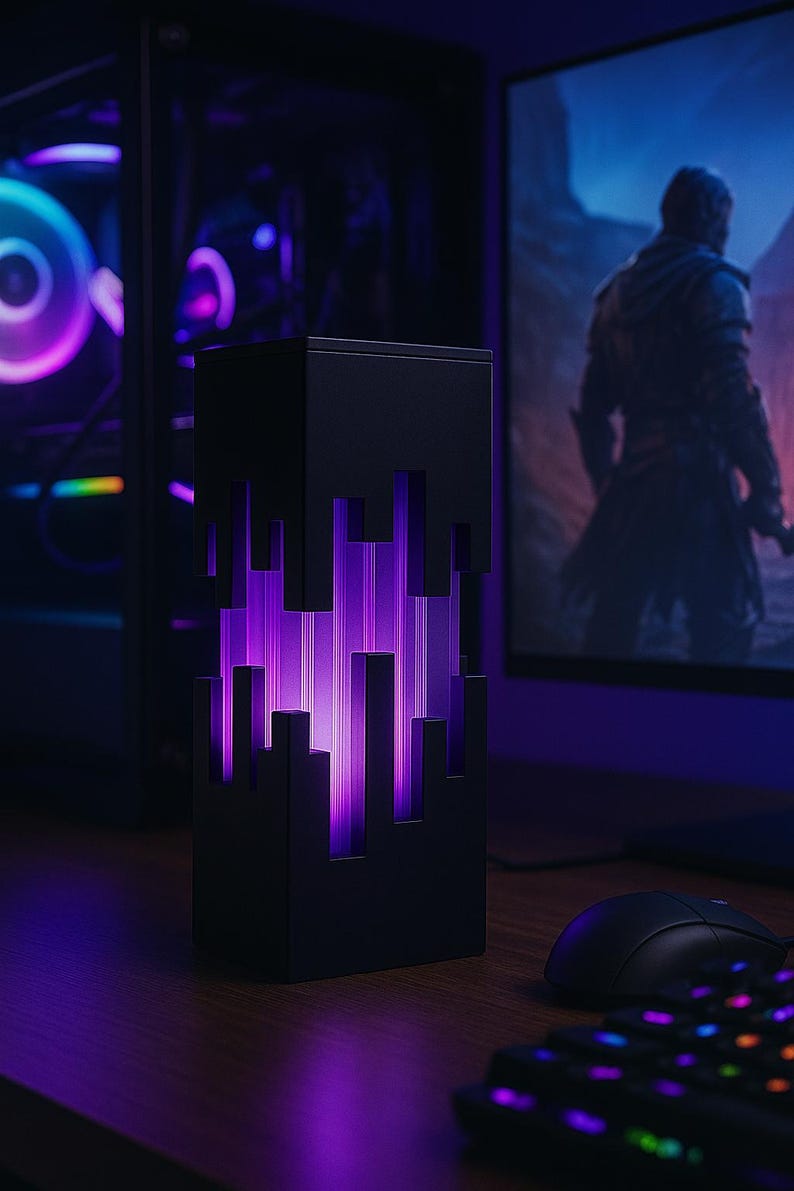 May include: A black, rectangular desk lamp with a pixelated design on the front, emitting a vibrant purple glow. The lamp is on a wooden desk, next to a computer mouse and keyboard. A computer monitor displays a game scene.