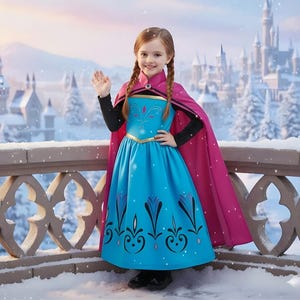 May include: A young girl in a blue and pink costume, reminiscent of a princess, stands on a snowy balcony. The costume includes a blue dress with decorative patterns, a pink cape, and a black long-sleeved top. A castle is visible in the background.
