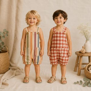 May include: Two children wearing sleeveless rompers. One romper features vertical stripes in muted tones of blue, orange, and cream with two front pockets. The other romper has a red and white gingham check pattern with two front pockets.