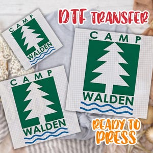 May include: DTF transfer sheets with a green and white Camp Walden design featuring a tree and wavy blue lines. The text "Camp Walden" is displayed on a grid background. The words "Ready to Press" are also visible.