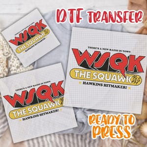 May include: DTF transfer sheets featuring the "WSQK The Squawk" radio station logo in red, yellow, and black. The design includes the text "There's a new radio in town" and "Hawkins Hitmaker!" on a grid background. The words "Ready to Press" are also visible.