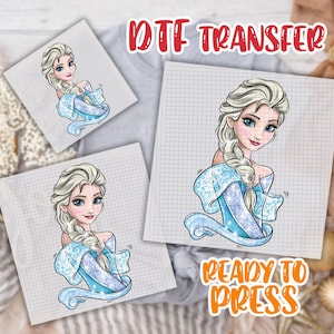 May include: DTF transfer sheets featuring a cartoon illustration of a blonde woman with a blue dress and the text "DTF TRANSFER" and "READY TO PRESS". The image is on a grid paper background.