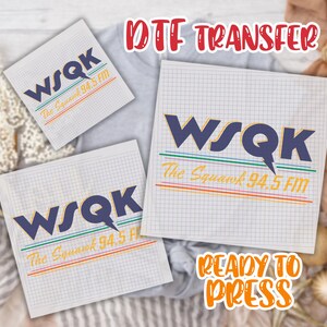 May include: DTF transfer sheets featuring the WSQK radio station logo in navy blue and yellow. The text "The Squawk 94.5 FM" is also included. The words "Ready to Press" are in orange. The sheets are on a grid background.