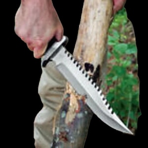 May include: A large, silver survival knife with a serrated edge and a black handle. The knife is being used to cut into a piece of wood. The blade is sharp and the knife appears to be sturdy.