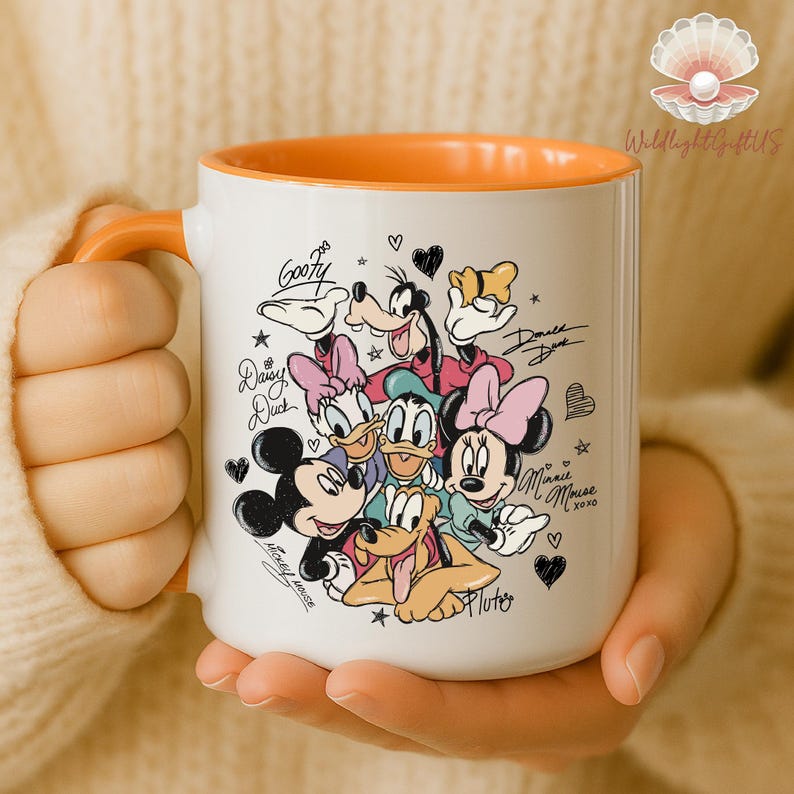 A person is holding a white mug with an illustration of Disney characters, including Mickey Mouse, Minnie Mouse, Donald Duck, Goofy, and Pluto.
