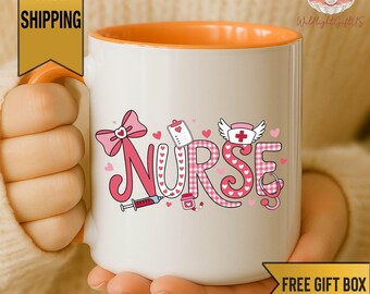 May include: A white ceramic mug with an orange interior and handle, featuring the word NURSE in large pink and white checkered letters. The design includes a pink bow, a medical clipboard, a syringe, a pill bottle, and a nurse cap with a red cross.