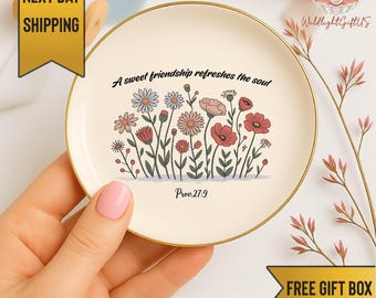 May include: A round, cream-colored trinket dish with a gold rim. The dish features a floral design with various flowers in pink, red, and blue. The text "A sweet friendship refreshes the soul" and "Prov.27:9" are also printed on the dish.