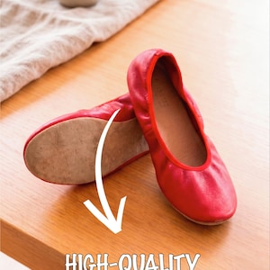 May include: A pair of red leather ballet flats. The shoes are displayed on a wooden surface, with the text "HIGH-QUALITY BREATHABLE LEATHER" below. A small vase and cloth are in the background.