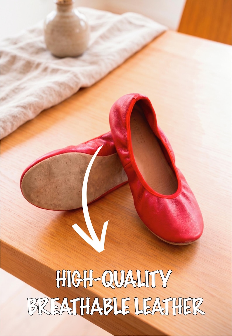 May include: A pair of red leather ballet flats. The shoes are displayed on a wooden surface, with the text "HIGH-QUALITY BREATHABLE LEATHER" below. A small vase and cloth are in the background.