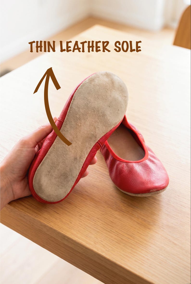 May include: Red ballet flats with thin leather soles. One shoe is held up to show the sole, with the text "THIN LEATHER SOLE" above. The other shoe is on a wooden surface.