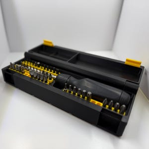 May include: A black screwdriver set with a variety of bits, neatly organized in a black case with yellow accents. The set includes a black handle and multiple screwdriver heads for various tasks.