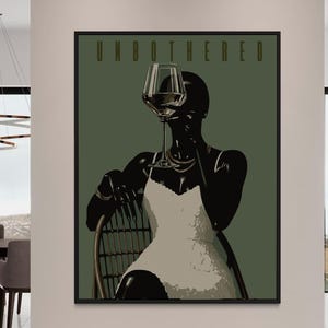 Puede incluir: Una impresión artística enmarcada que presenta una ilustración estilizada de una persona sosteniendo una copa de vino. La obra de arte utiliza tonos de negro, blanco y verde oliva, con la palabra "UNBOTHERED" en la parte superior. La persona lleva un vestido blanco y joyas.