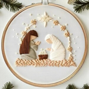 May include: Embroidered artwork in a wooden hoop depicts a nativity scene. Two figures in robes kneel before a manger. The scene is framed by a star and floral accents in beige and cream tones, set against a white background.
