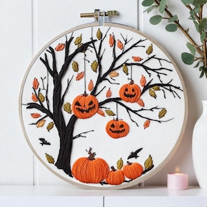 May include: Embroidered Halloween hoop art showing a black tree with orange jack-o'-lanterns suspended from the branches. The design includes orange, yellow, and green leaves, and black bats. The artwork is set in a wooden hoop.