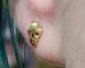 May include: Gold hammered ear cuff with a textured surface. The ear cuff is worn in the upper ear lobe.