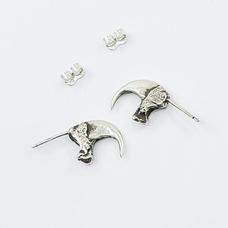 May include: A pair of silver claw earrings. Each earring features a detailed claw design with a textured surface.