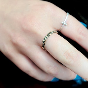 May include: A gold ring with a textured surface featuring a leopard print design. The ring is worn on a finger.
